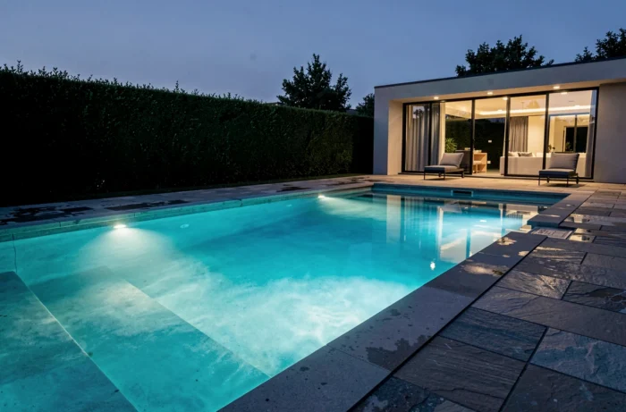 Éclairage LED submersible à variation de température de couleur dans une piscine moderne au crépuscule avec reflets lumineux dans l'eau
