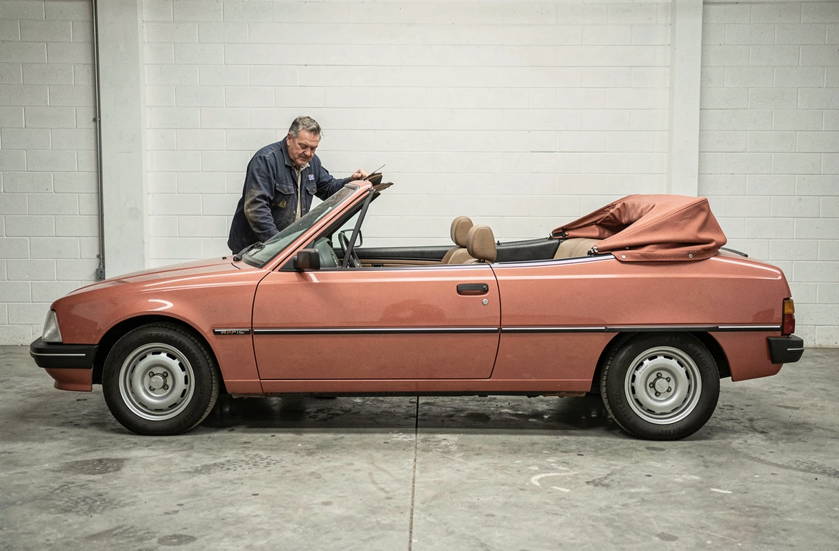 Mécanicien inspectant une Peugeot 305 cabriolet rouge corail restaurée dans un garage en béton, profil complet du véhicule visible